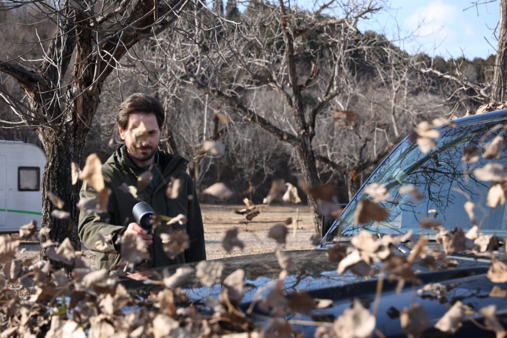 Booster TF64C Cordless Leaf Blower Clearing fallen leaves piled up on the car