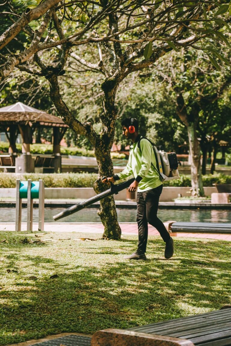 A man using a leaf blower in a vibrant Kuala Lumpur park, showcasing daily outdoor maintenance.